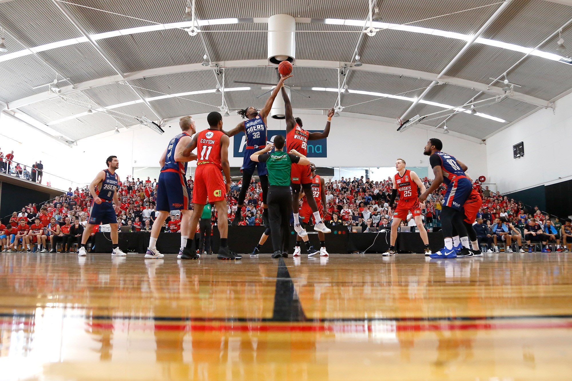 A low angle photo of basketballers competing in front of a crowd