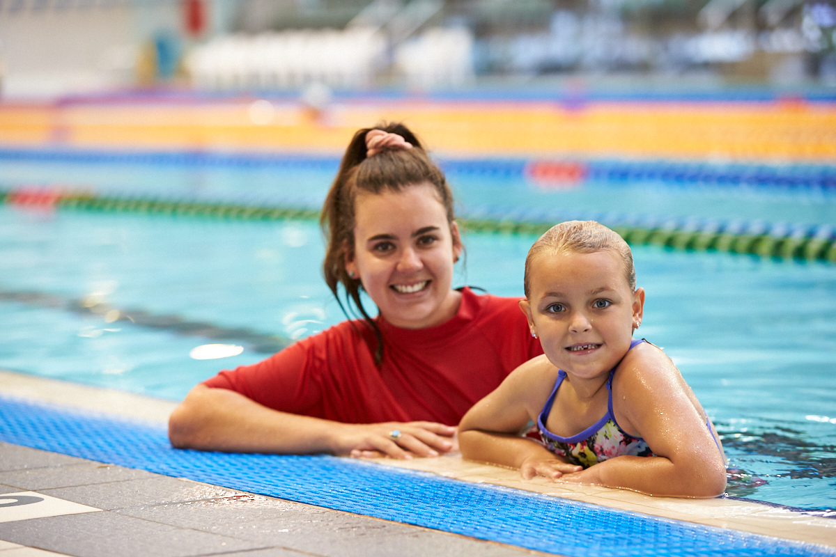 Swim instructor with student at the water's edge of the pool