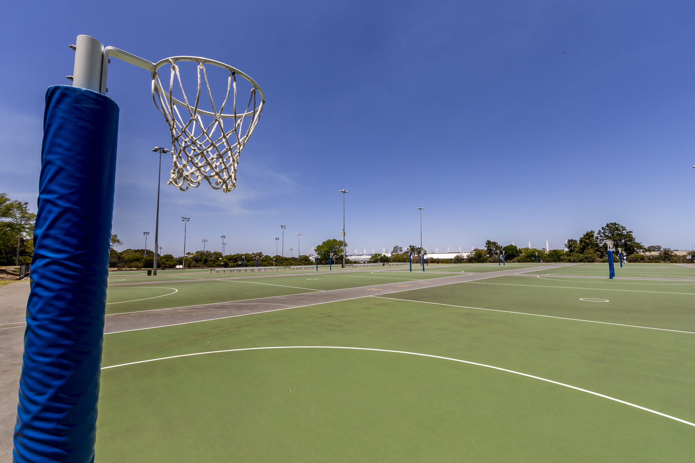 A photo of a netball hoop with multiple outdoor netball courts in the background at Arena Joondalup
